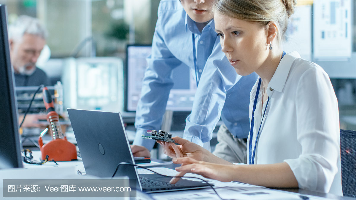 女計算機科學家將電路板連接到她的筆記本電腦并開始編程。她在先進技術實驗室工作。