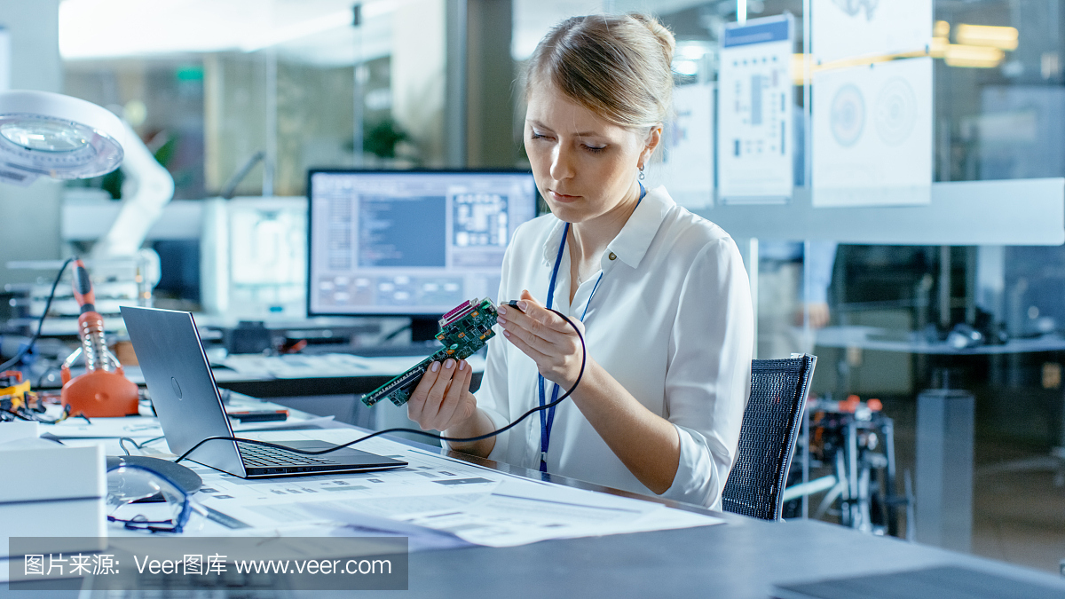 女計算機科學家將電路板連接到她的筆記本電腦并開始編程。她在先進技術(shù)實驗室工作。